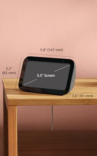Smart display device on a wooden table with dimensions labeled.