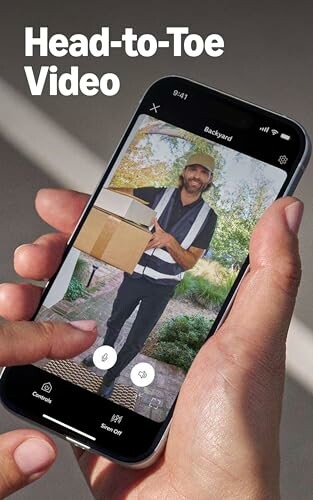 Person holding smartphone with doorbell camera video showing delivery person.